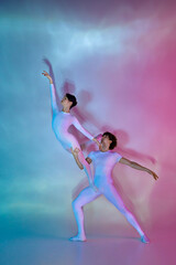 Ballet duo mid-performance, male dancer lifting female dancer against colorful gradient background with light play. Concept of beauty and elegance, dance grace, inspiration, creativity.