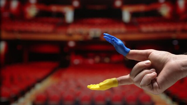 Tiny hand puppet clapping in an empty theater