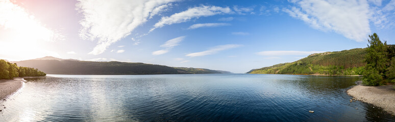 Panoramic drone shot of Loch Ness, where the gentle rays of the sun bathe the tranquil waters and...