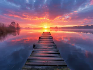 Deurstickers Wooden jetty extends into a calm lake reflecting a vibrant sunset with clouds painted across the sky. © burntime555