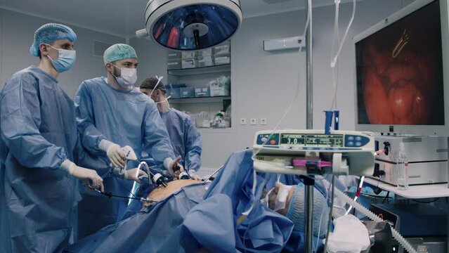 A group of medical surgeons in the operating room during an operation. A patient on the operating table during laparoscopic abdominal surgery. The concept of modern medical equipment.