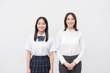 生徒と先生がカメラ目線で並んで立っている/スタジオ撮影白背景	
