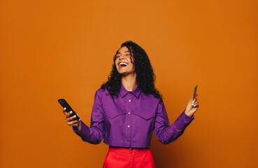 Excited woman makes online payment with credit card on orange background - 773852541