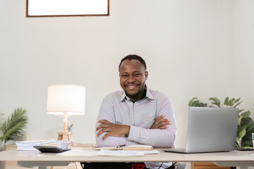 Young African American businessman uses laptop to work on white wooden table in office room. - Powered by Adobe