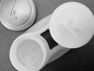 Macro closeup of a contact lens pot, with the left side lid removed and the contact lens submerged in solution.