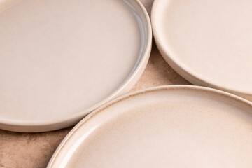 Beige ceramic dinner plates on a brown stone tabletop.