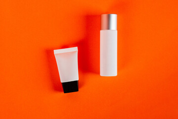 Plastic white tube for cream or lotion. Skin care or sunscreen cosmetic on orange background.