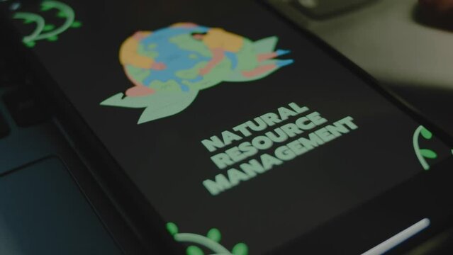 Natural resources management inscription on black background on smartphone screen. People protect Planet Earth image. Environment concept. Male hand flapping fingers cheerfully