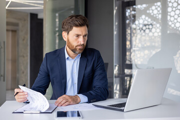 Serious accountant deep in thought over financial paperwork