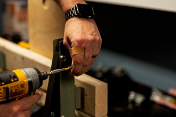 a man works with wood panels and tools in his workshop. real life. rough hands, finger covered with...