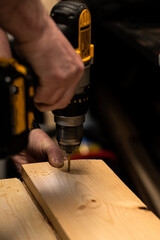 a man works with wood panels and tools in his workshop. real life. rough hands, finger covered with adhesive tape.