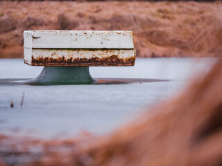Old dirty panel of Styrofoam on melted frozen lake surface shows how cold winter was and how deep water got frozen. Nature scene. Visual representation of ice deepness in cold season. Nobody