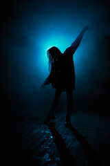 cinematic silhouette of a dancing woman with blue lights and fog in the background. 