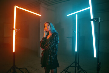 Creative portrait of a young women posing in front of lightbars. Vivid Colors in teal and orange....
