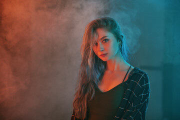 Portrait of a young women standing in haze. Vivid Colors in teal and orange. 
