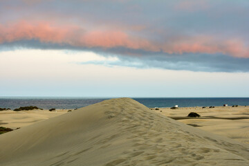 In the dunes of Maspalomas on Gran Canaria in Spain. View of the sea in the evening light with clouds and blue sky - 773874398