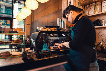 Barista working behind the counter in the cafe, getting ready to make coffee. - obrazy, fototapety, plakaty