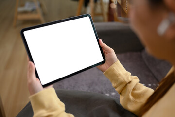 Happy teenage woman in glasses using digital tablet on couch at home