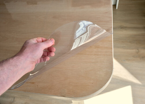 Protective tablecloth in transparent plastic, on a plywood kitchen table.