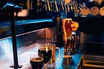 Bartender serving tall, frothy amber beer with row of taps and other beers, ales in background. Serving craft beer from tap. Concept of alcohol drinks, nightlife, party, festivals, Oktoberfest. Ad - obrazy, fototapety, plakaty