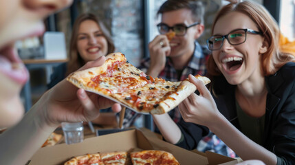 a group of office workers gathered around a table, eating pizza and laughing