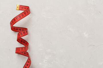 Measuring tape on concrete background, top, view