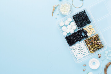 Tools and beads for making handmade jewelry on color background, top view