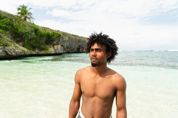 Portrait of black boy with afro hair on a beach with turquoise water. smiling boy. Paradise Beach.