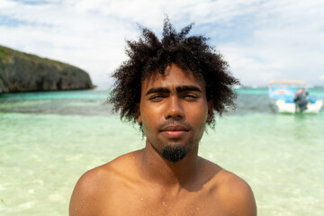 Portrait of black boy with afro hair on a beach with turquoise water. smiling boy. Paradise Beach.