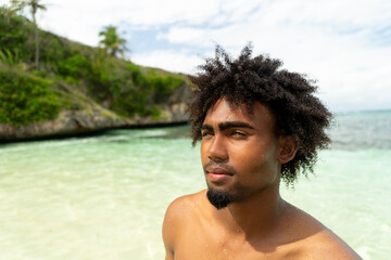 Portrait of black boy with afro hair on a beach with turquoise water. smiling boy. Paradise Beach.