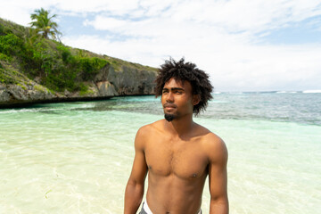 Portrait of black boy with afro hair on a beach with turquoise water. smiling boy. Paradise Beach.