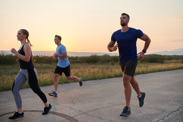 A diverse group of runners trains together at sunset.