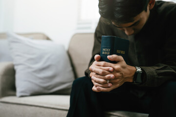 Christian pray and worship god with belief and spirituality. Hand praying and praise with the holy bible in church. young man prayer confession sin for seeking peace relationship in Jesus christ - obrazy, fototapety, plakaty