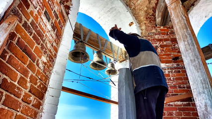 Bells in a Brick Bell Tower Against a Daytime Sky. The ringing of bells for the Orthodox Easter...