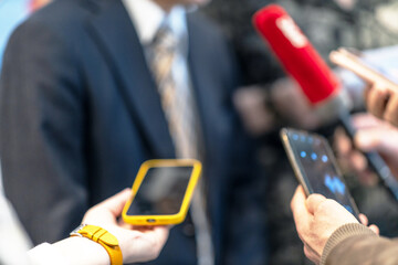 News conference, journalists holding microphone and smartphone interviewing unrecognizable...