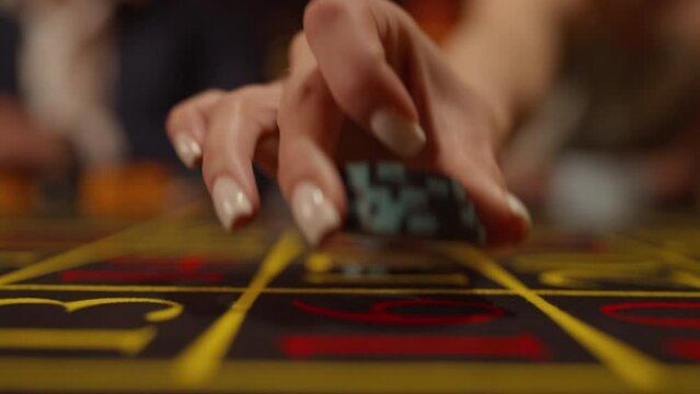 A female casino player places chips during the game. Close-up of the hand