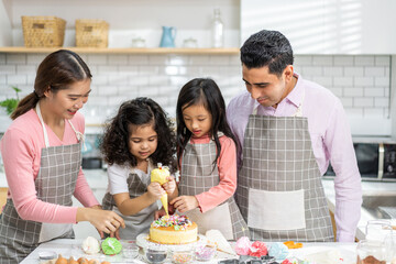 Portrait of enjoy happy love asian family father and mother with little asian girl daughter child play and having fun cooking food together with baking cookie and cake ingredient in kitchen