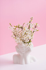 Head shape vase with spring bloom on pink background. Spring inspiration, mental health concept