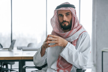 Normal work day. Successful Muslim businessman in traditional outfit in his office
