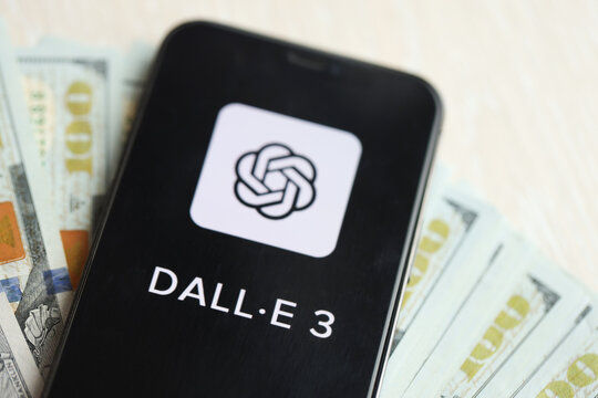 KYIV, UKRAINE - MARCH 17, 2024 Dall-E 3 logo on iPhone display screen with many hundred dollar bills. Artificial Intelligence engine