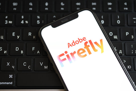 KYIV, UKRAINE - MARCH 17, 2024 Adobe Firefly logo on iPhone display screen and MacBook keyboard. Artificial Intelligence engine