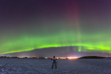A small figure of a man against the backdrop of the polar lights.