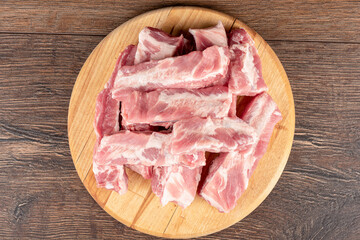 Top view of a bunch of sliced raw pork ribs round on a cutting board.