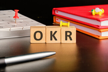 OKR . Objectives and Key Results OKR concept on wooden cubes with a calculator and notebooks on a...