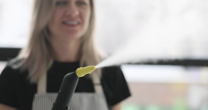 Cleaning lady holding steamer in hands and pressing on it closeup 4k movie slow motion. Cleaning services concept