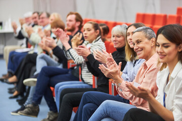 Smiling audience applauding at business event in auditorium