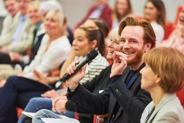 Smiling audience answering during business conference in auditorium