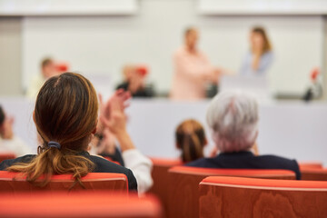 Woman in audience during business conference in auditorium