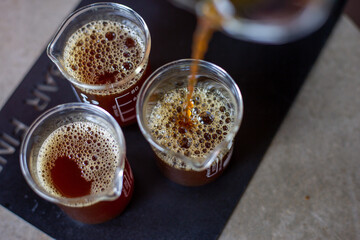 selective focus black coffee in a clear glass Pouring coffee from a glass pitcher into a clear measuring glass with numbers indicating the amount on the side of the glass.