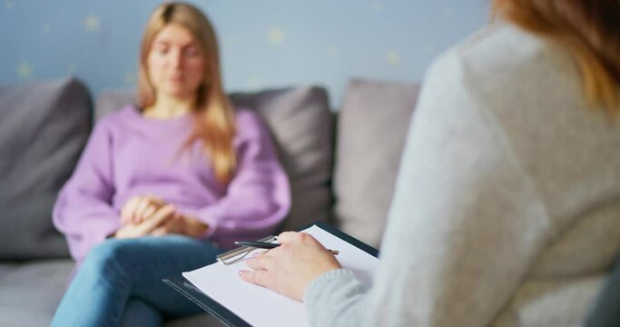 Woman in counseling session with blurred therapist in foreground